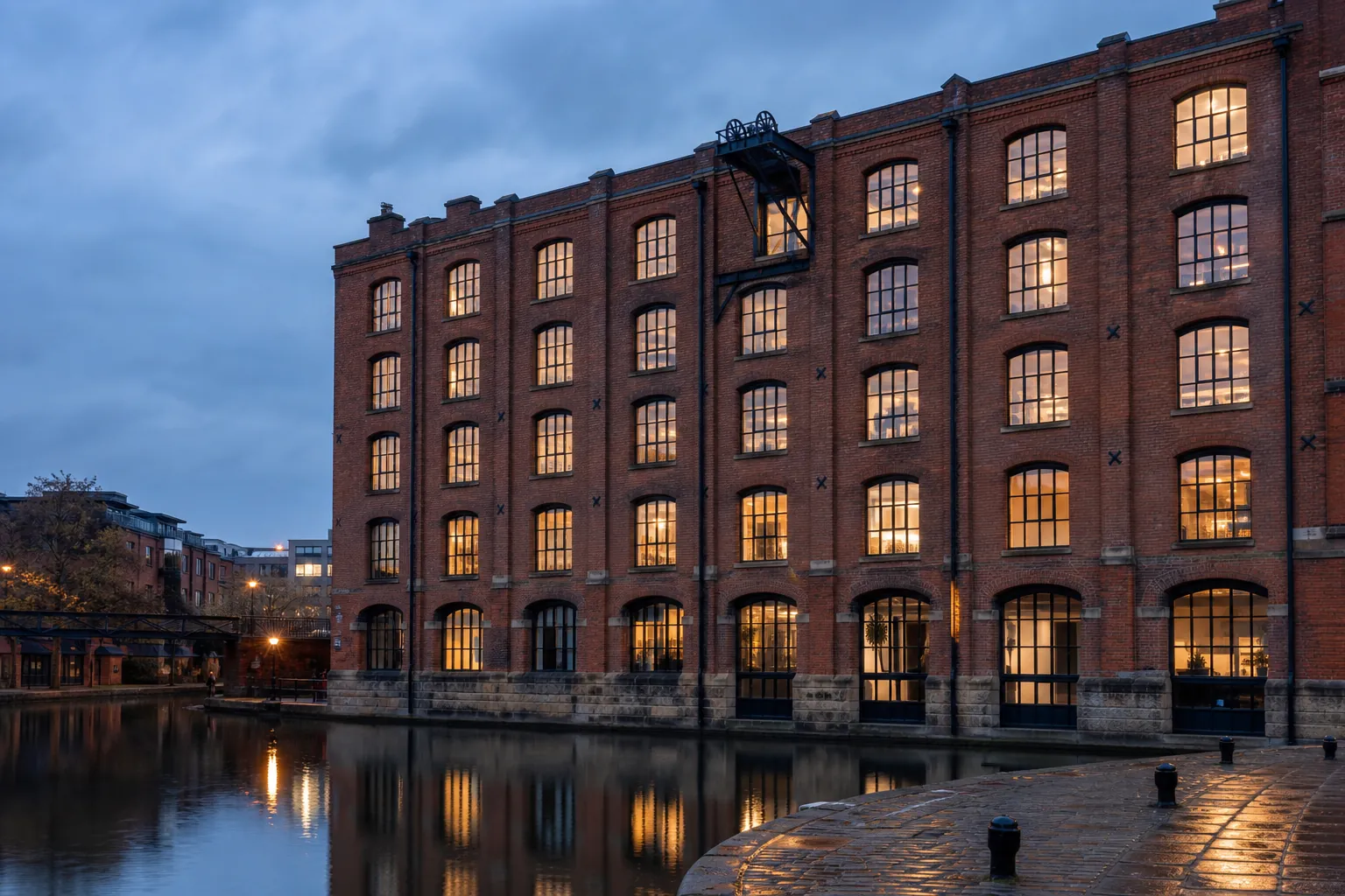 Ashfold Mill, a converted brick textile warehouse on Piccadilly Basin, Manchester, seen across the canal at dusk